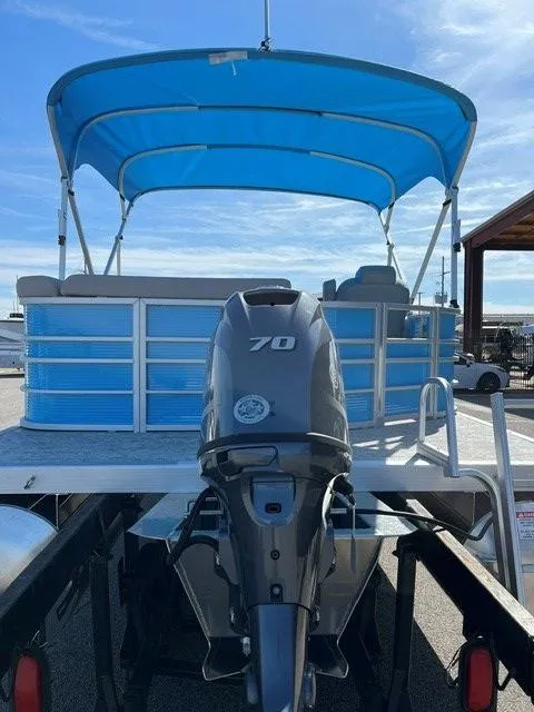 Slide: The Image of 2025 Bennington 20L Cruise pontoon boat with blue canopy and 70 HP outboard motor. - 2