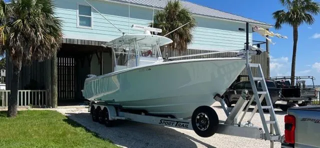 Slide: The Image of 2023 Contender 35 ST boat on trailer, parked near a coastal house with palm trees. - 1