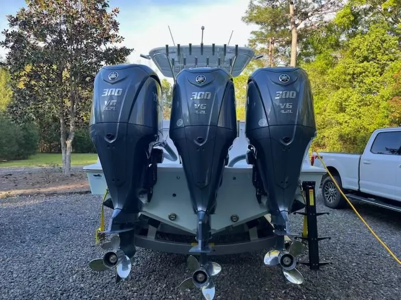 Slide: The Image of 2023 Contender 35 ST boat with triple 300 HP outboard engines, parked outdoors. - 4