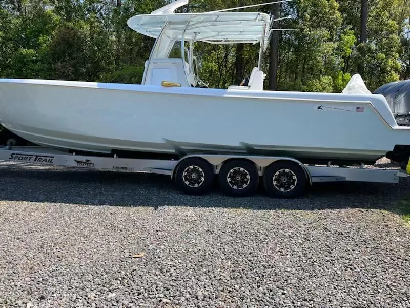 Slide: The Image of 2023 Contender 35 ST boat on trailer, parked outdoors, surrounded by trees. - 6