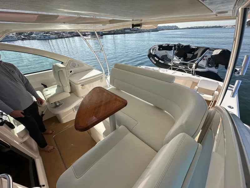 Slide: The Image of 2013 Tiara Yachts 3900 Open interior with white seating and wooden table, docked by the water. - 35