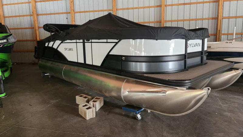 The Image of A 2026 Sylvan L3 pontoon boat is stored on concrete blocks in a warehouse. - 0