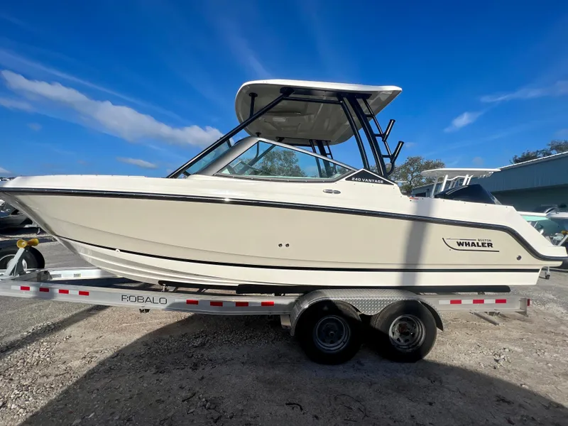 Slide: The Image of 2025 Boston Whaler 240 Vantage boat on trailer under clear blue sky. - 4