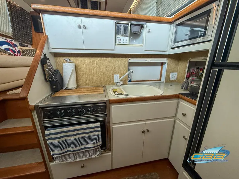 Slide: The Image of Compact kitchen in 1995 Carver 430 Cockpit Motor Yacht with stove, sink, and cabinets. - 28