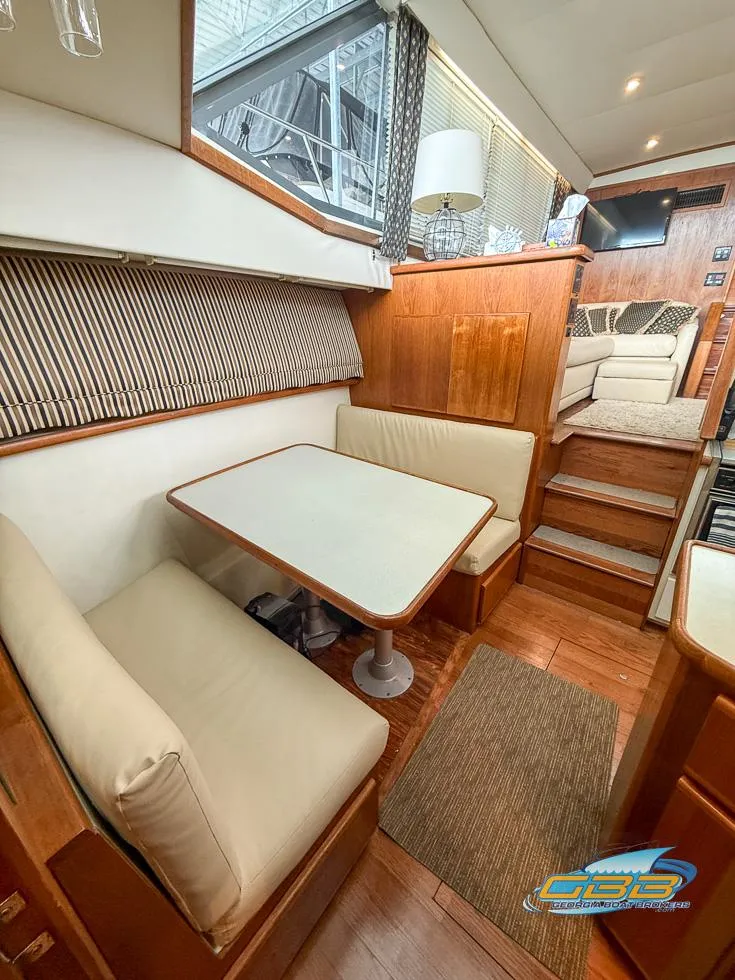 Slide: The Image of 1995 Carver 430 Cockpit Motor Yacht interior with dining area and stairs, featuring wood accents. - 30
