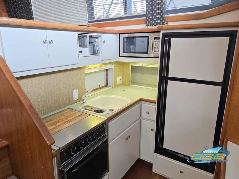 Slide: The Image of 1995 Carver 430 Cockpit Motor Yacht kitchen with stove, sink, microwave, and refrigerator. - 4