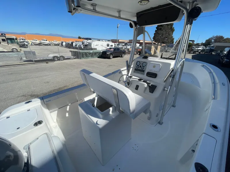 Slide: The Image of 2007 Tidewater 216 CC Adventure boat interior with console and seating, parked outdoors. - 22