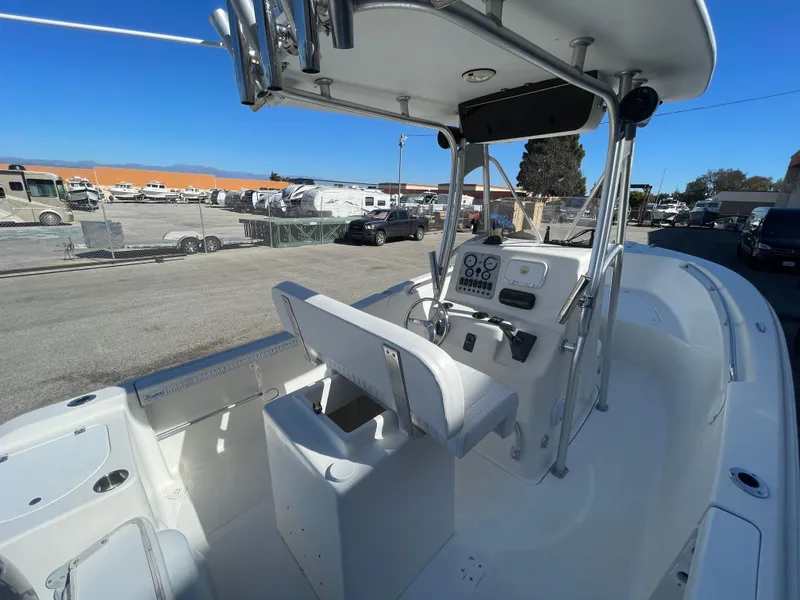 Slide: The Image of 2007 Tidewater 216 CC Adventure boat interior with console and seating, parked outdoors. - 23