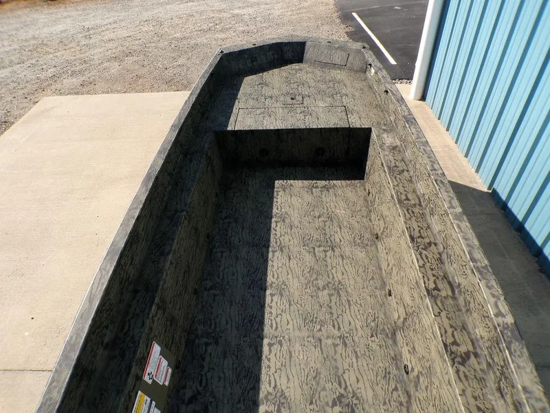 Slide: The Image of 2025 Tracker Grizzly® 1650 T Prairie Wings Edition boat, camo interior, parked near blue building. - 8
