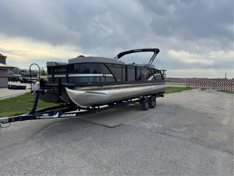 Slide: The Image of 2023 Sylvan L5 DLZ Bar pontoon boat on trailer under cloudy sky. - 0