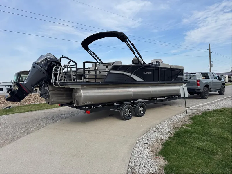 Slide: The Image of 2023 Sylvan L5 DLZ Bar pontoon boat on trailer, parked on a driveway. - 19