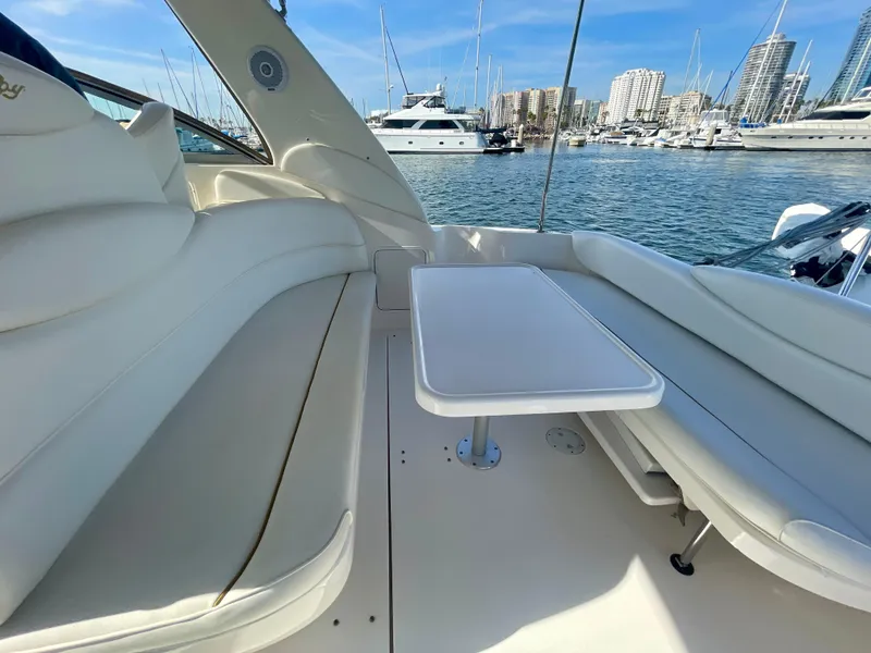 Slide: The Image of 2001 Sea Ray 340 Sundancer interior with white seating and table, docked at marina. - 14
