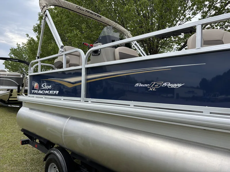 Slide: The Image of 2025 Sun Tracker Bass Buggy 16 XL Select pontoon boat on display outdoors. - 4
