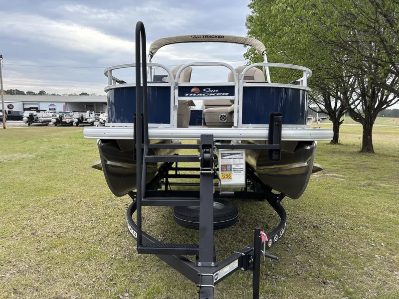 Slide: The Image of 2025 Sun Tracker Bass Buggy 16 XL Select pontoon boat on trailer, parked on grass. - 5
