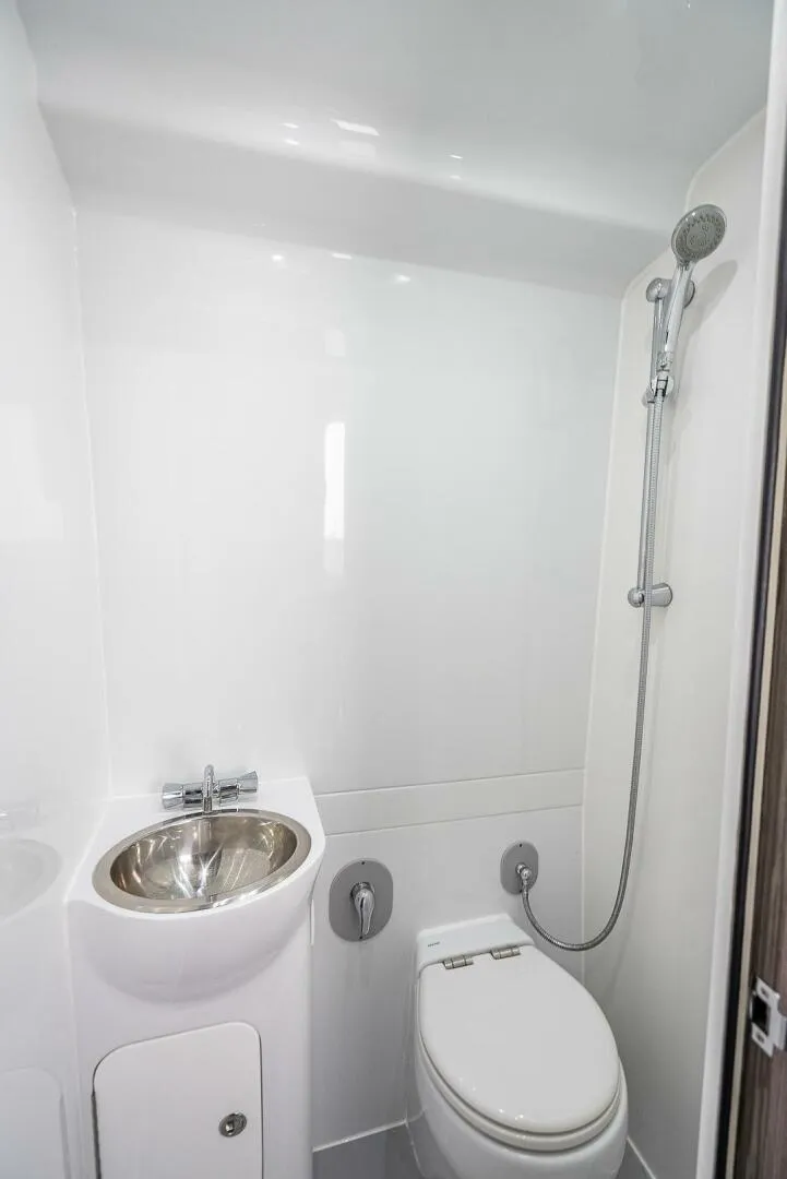 Slide: The Image of 2024 Yellowfin 54 Offshore bathroom with shower, sink, and toilet in sleek white design. - 33