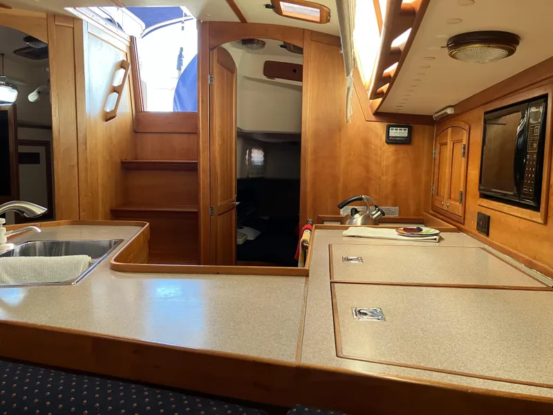 Slide: The Image of Interior of a 1997 Sabre 402 yacht, featuring a wooden kitchen and stairs. - 13