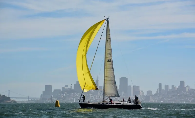 Slide: The Image of Sailboat Sabre 402 (1997) with yellow spinnaker on water, city skyline in background. - 3