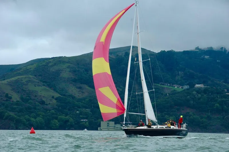 Slide: The Image of Sailing yacht Sabre 402 (1997) with colorful spinnaker on a scenic waterway. - 4