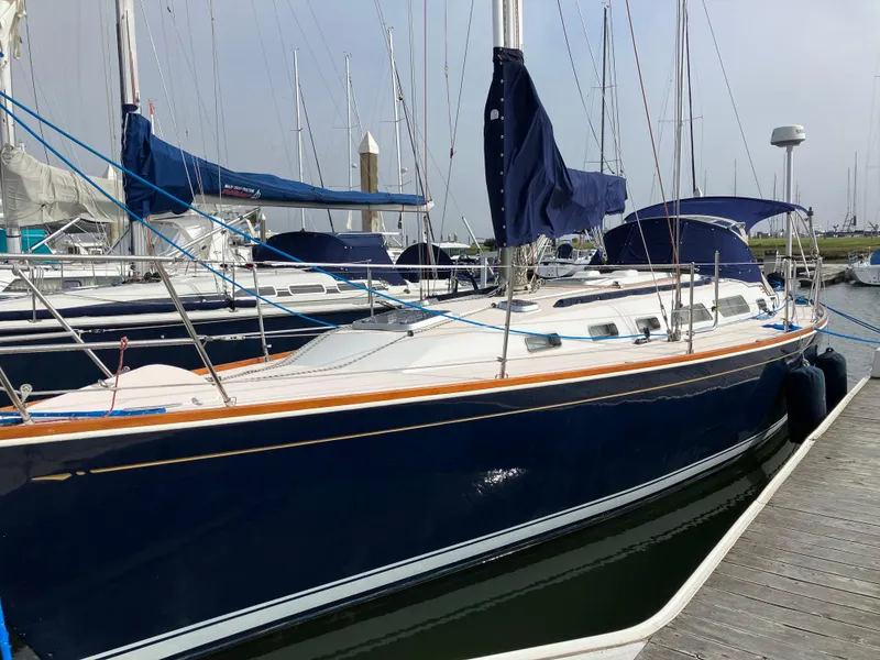 Slide: The Image of 1997 Sabre 402 sailboat docked at marina with blue hull and covered sails. - 7