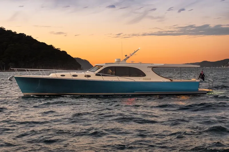 Slide: The Image of 2026 Palm Beach Motor Yachts PB50 cruising at sunset near a scenic coastline. - 0