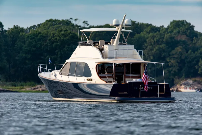 Slide: The Image of 2026 Palm Beach Motor Yachts PB70 cruising on a serene lake with lush green backdrop. - 17