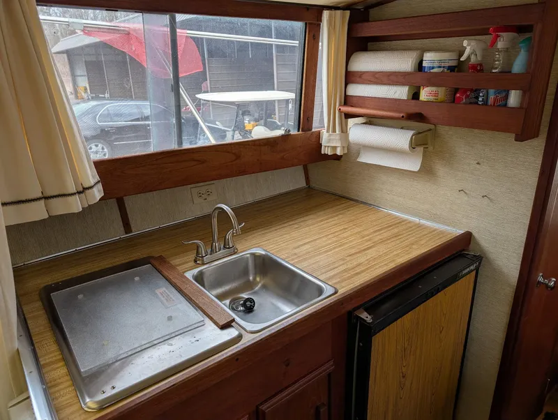 Slide: The Image of 1989 Marinette 28 Sport Fish Fly Bridge kitchen with sink, countertop, and storage shelves. - 10