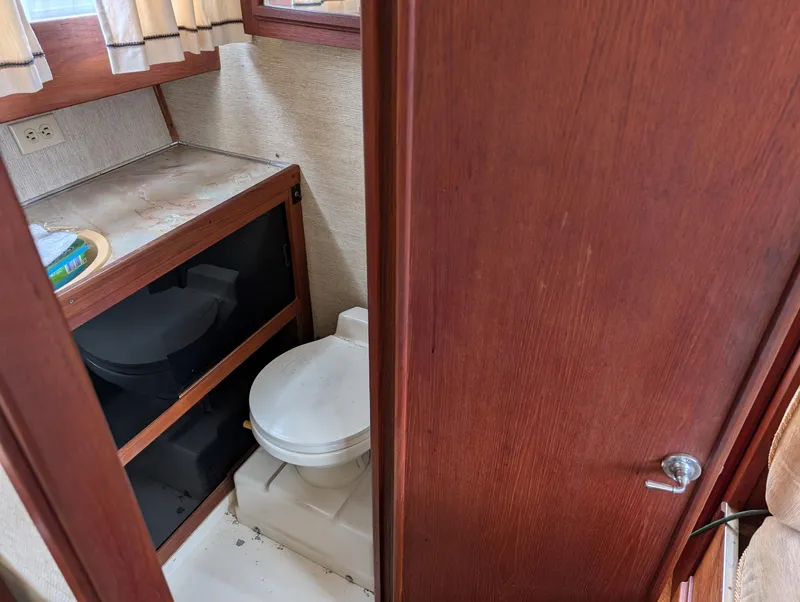 Slide: The Image of 1989 Marinette 28 Sport Fish Fly Bridge bathroom with wooden cabinetry and compact toilet. - 8