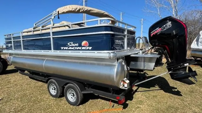 Slide: The Image of 2025 Sun Tracker Fishin' Barge 20 DLX pontoon boat on trailer, outdoor setting. - 3