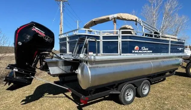 Slide: The Image of 2025 Sun Tracker Fishin' Barge 20 DLX pontoon boat on trailer, outdoor setting. - 6