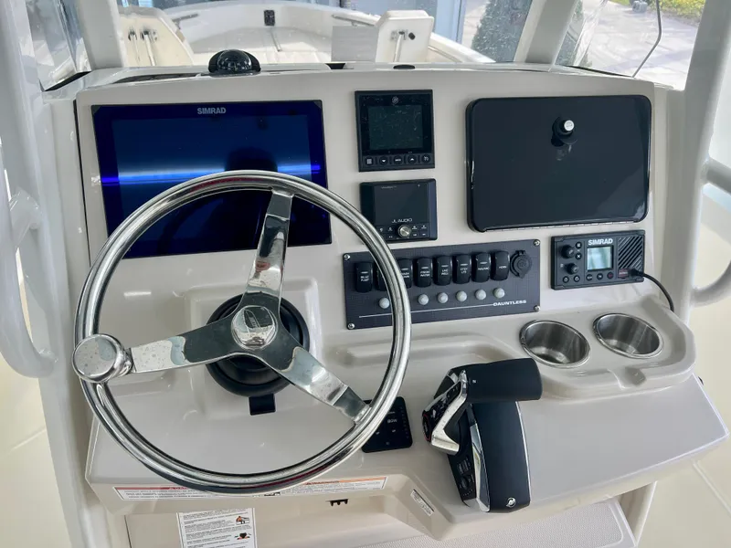 Slide: The Image of 2025 Boston Whaler 250 Dauntless helm with steering wheel, controls, and navigation displays. - 12