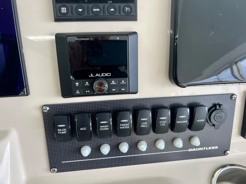 Slide: The Image of Control panel of 2025 Boston Whaler 250 Dauntless with JL Audio system and switches. - 13