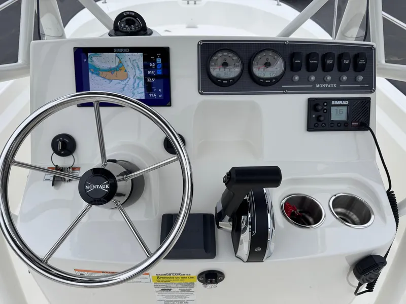 Slide: The Image of Boston Whaler 190 Montauk 2023 boat dashboard with steering wheel and navigation instruments. - 10