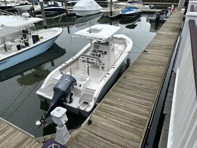 Slide: The Image of 2018 Sea Fox 266 Commander boat docked at a marina, featuring a sleek design and outboard motor. - 2