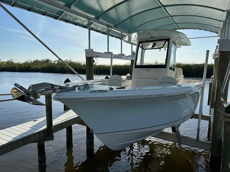 Slide: The Image of 2022 Sea Hunt Ultra 255 SE boat docked under a canopy on a sunny day. - 1