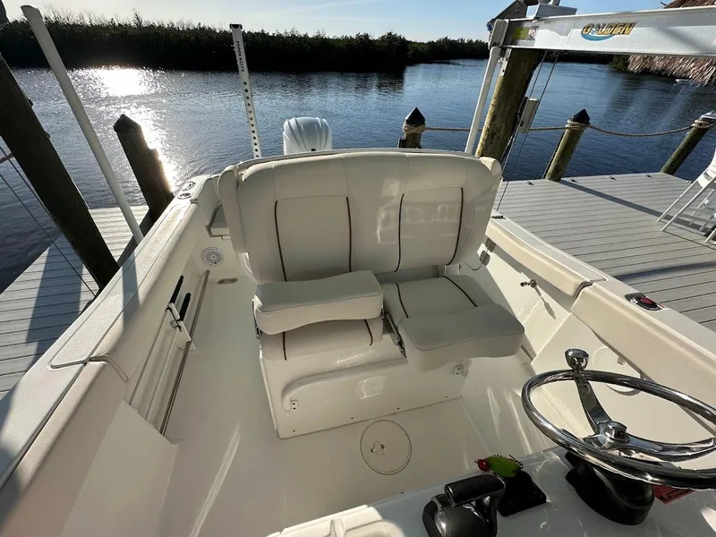 Slide: The Image of 2022 Sea Hunt Ultra 255 SE boat interior with white seating and steering wheel by the water. - 12