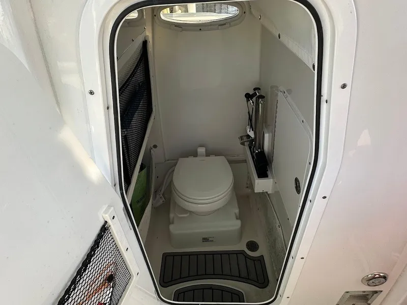 Slide: The Image of 2022 Sea Hunt Ultra 255 SE boat interior bathroom with toilet and storage compartments. - 15