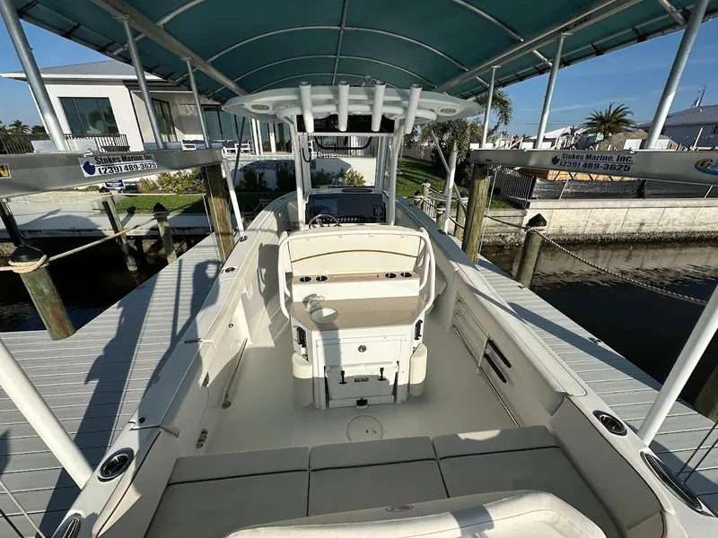Slide: The Image of 2022 Sea Hunt Ultra 255 SE boat docked under canopy, showcasing spacious interior and seating. - 5