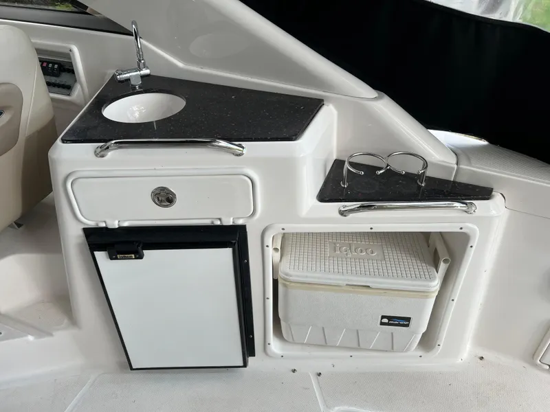 Slide: The Image of 2013 Regal 30 Express boat kitchenette with sink, mini fridge, and storage compartment. - 14