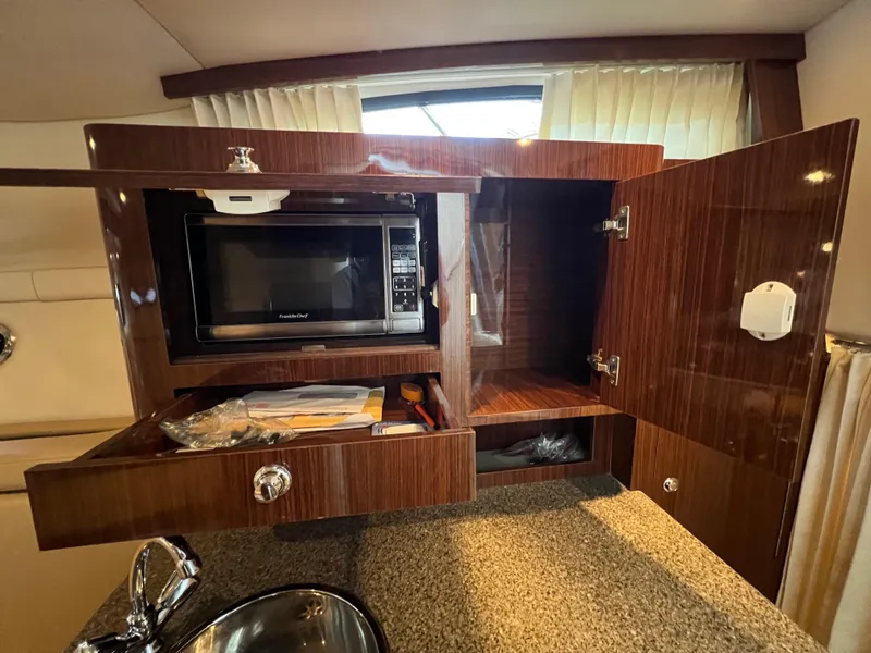 Slide: The Image of 2013 Regal 30 Express yacht kitchen with microwave, open cabinets, and countertop. - 27