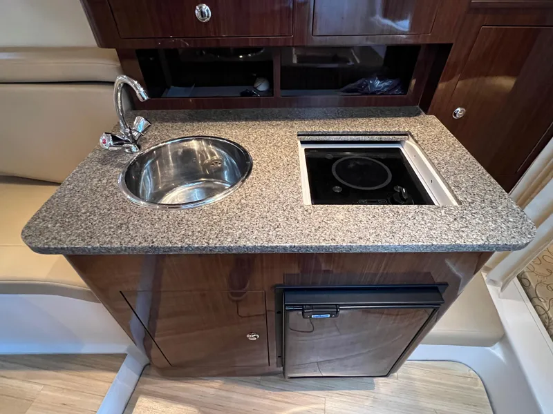 Slide: The Image of Compact kitchen area in a 2013 Regal 30 Express boat with sink and stove. - 28