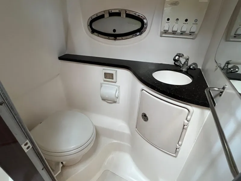 Slide: The Image of 2013 Regal 30 Express boat bathroom with sink, toilet, and storage cabinet. - 32