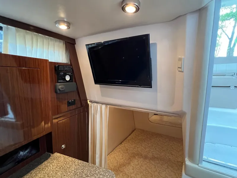 Slide: The Image of 2013 Regal 30 Express cabin interior with TV, wood paneling, and cozy sleeping area. - 35