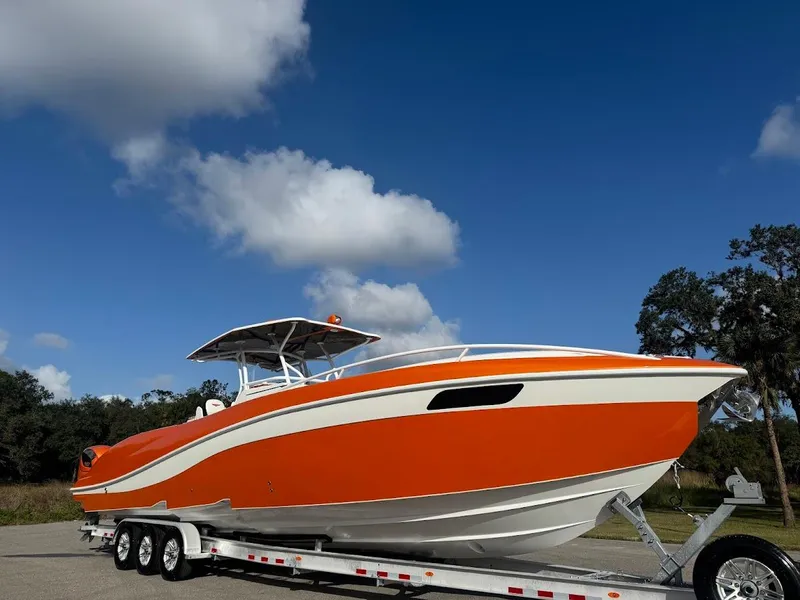 Slide: The Image of Orange 2015 Deep Impact 399 Cabin boat on trailer under blue sky. - 4