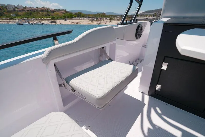 Slide: The Image of 2025 Ranieri NEXT 255 LX boat interior with foldable seat, near scenic coastline. - 32