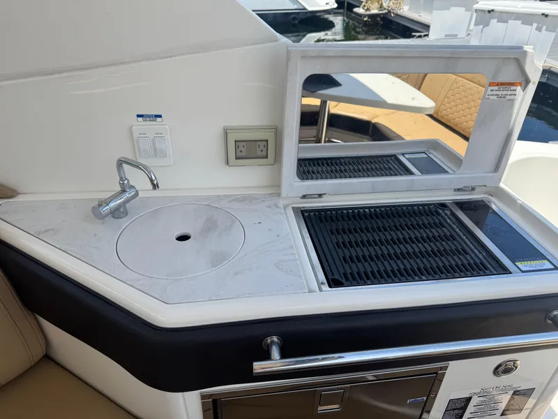 Slide: The Image of 2021 Sea Ray Sundancer 320 Coupe Outboard boat kitchen with sink and grill. - 15