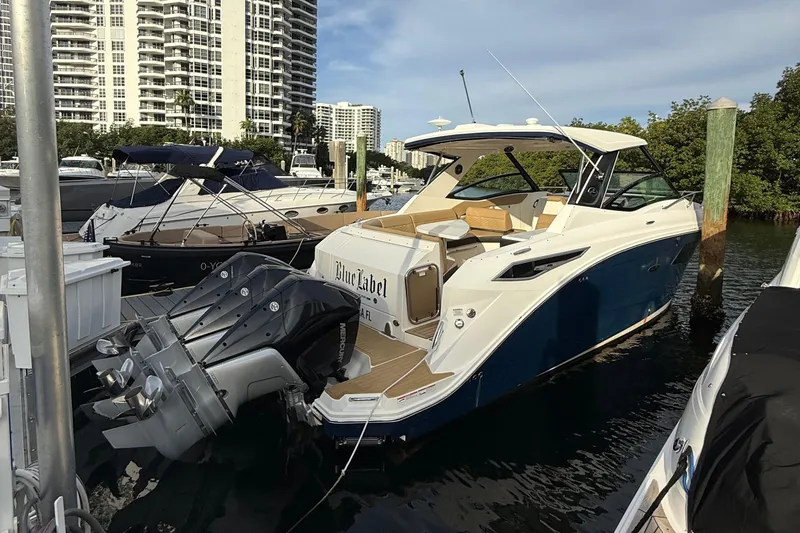 Slide: The Image of 2021 Sea Ray Sundancer 320 Coupe OB docked at marina, with modern design and powerful outboard engines. - 2