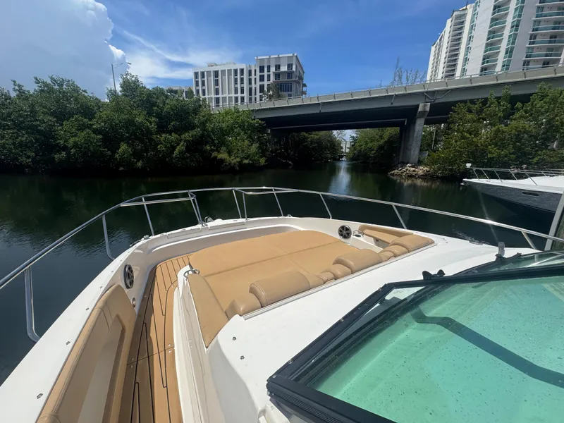 Slide: The Image of 2021 Sea Ray Sundancer 320 Coupe Outboard cruising under a bridge, surrounded by lush greenery. - 22