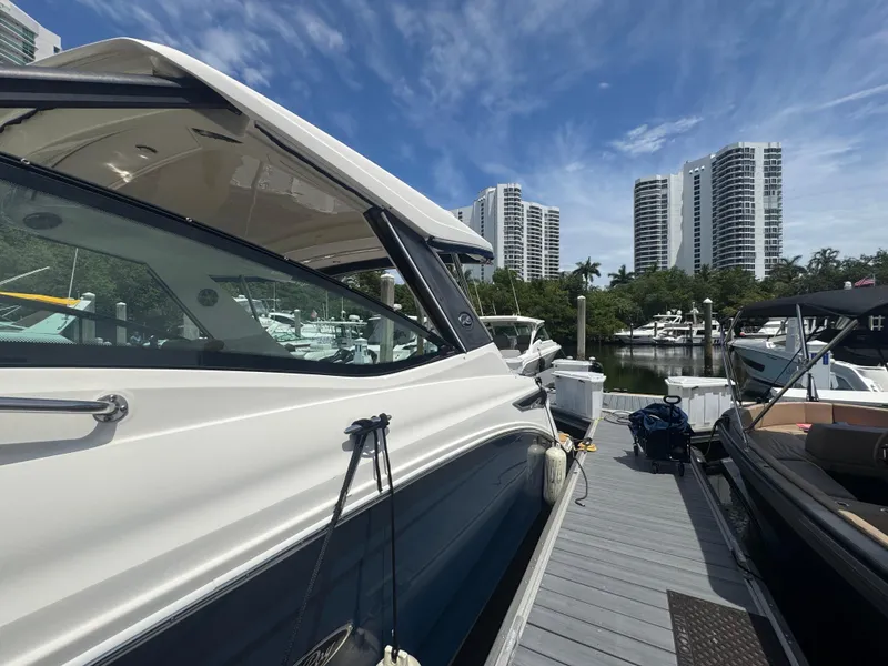 Slide: The Image of 2021 Sea Ray Sundancer 320 Coupe Outboard docked with city skyline backdrop. - 40