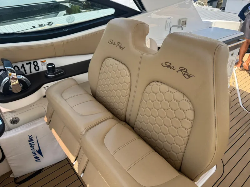 Slide: The Image of 2021 Sea Ray Sundancer 320 Coupe Outboard cockpit with tan leather seats and control panel. - 9