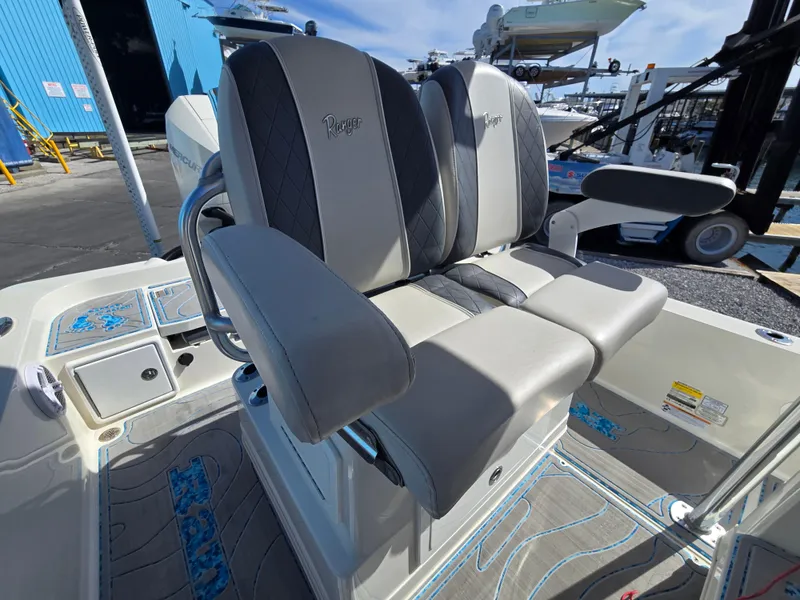 Slide: The Image of 2021 Ranger 2360 Bay boat seats with gray and black upholstery in a marina setting. - 14